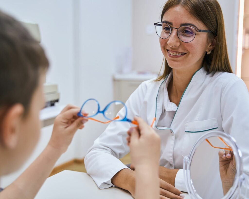 Opticienne qui fait essayer des lunettes à un enfant