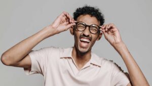 Homme qui rigole en tenant ses lunettes