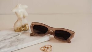 Lunettes de soleil posé à côté de bijoux et d'une bougie